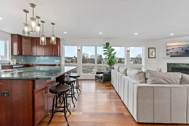 a kitchen with stainless steel appliances granite countertop a refrigerator a sink dishwasher a stove and a oven with wooden floor