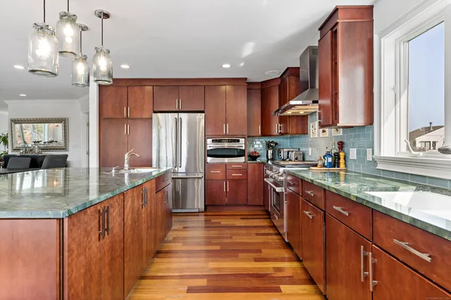 a kitchen with wooden cabinets a sink dishwasher a stove and a dining table with wooden floor