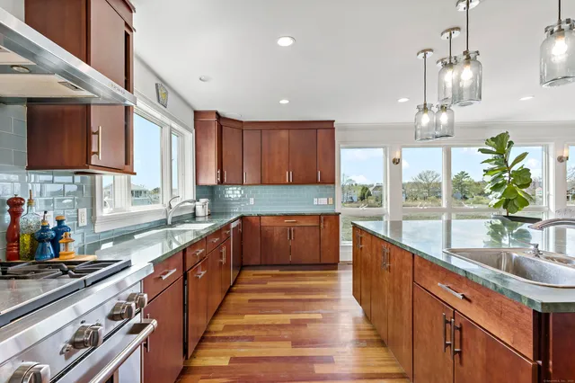 a kitchen with stainless steel appliances kitchen island granite countertop wooden floors and white cabinets