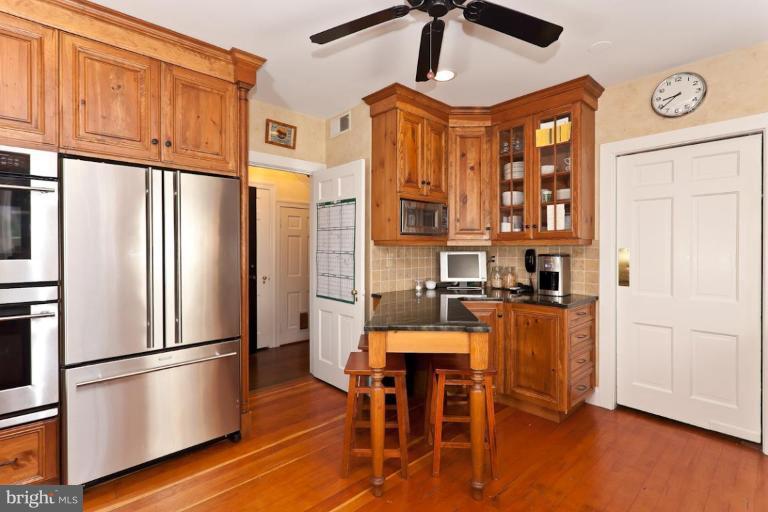 221 Tunbridge Road Baltimore, MD 21212 - Photo 9 of 14 a kitchen with stainless steel appliances granite countertop a refrigerator a microwave oven a dining table and chairs with wooden floor