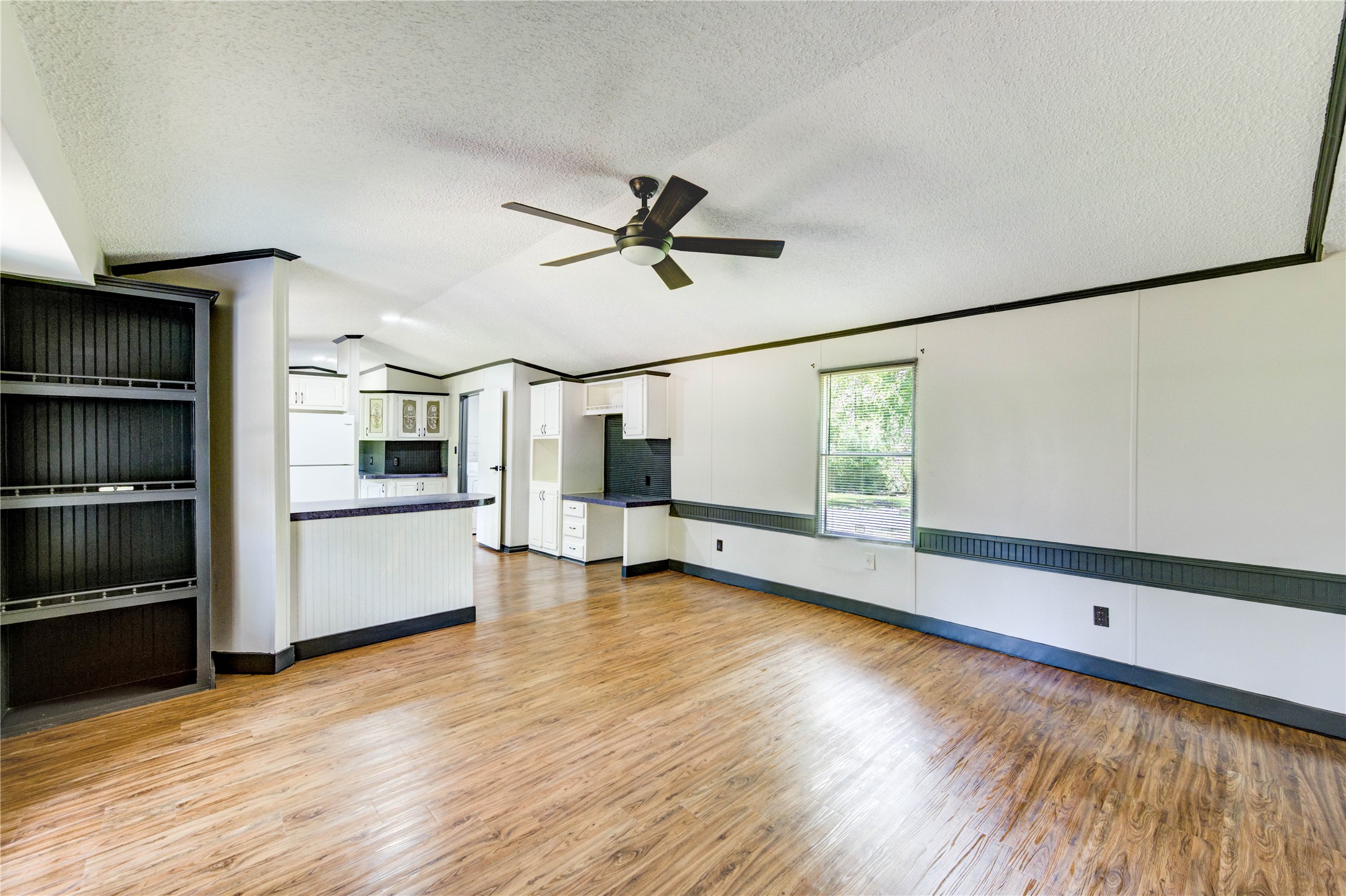 a view of empty room with wooden floor and ceiling fan
