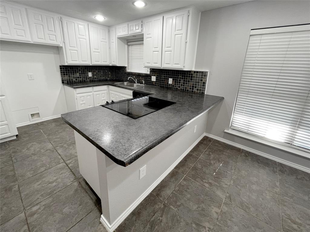 7716 Harmony Drive Fort Worth, TX 76133 - Photo 17 of 40 a kitchen with a sink a stove a microwave and cabinets
