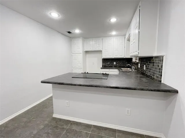 a kitchen with kitchen island granite countertop white cabinets and stainless steel appliances