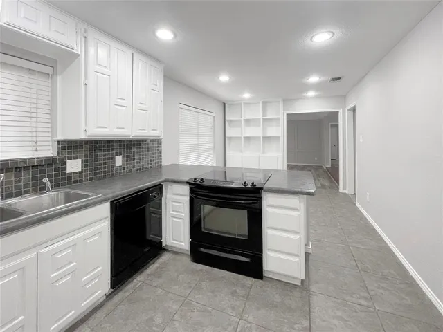 a kitchen with granite countertop white cabinets sink and stainless steel appliances