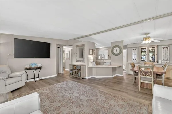 a living room with furniture a flat screen tv and kitchen view