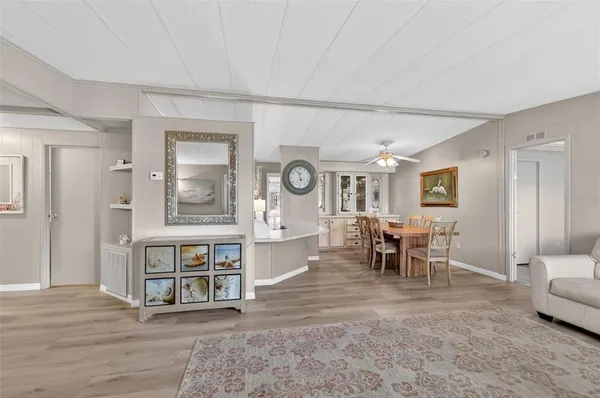 a living room with furniture and a dining table with wooden floor