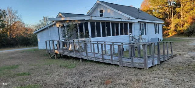 a view of a house with a wooden deck and a yard
