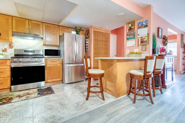 a kitchen with stainless steel appliances granite countertop a stove top oven a refrigerator and a dining table with wooden floor