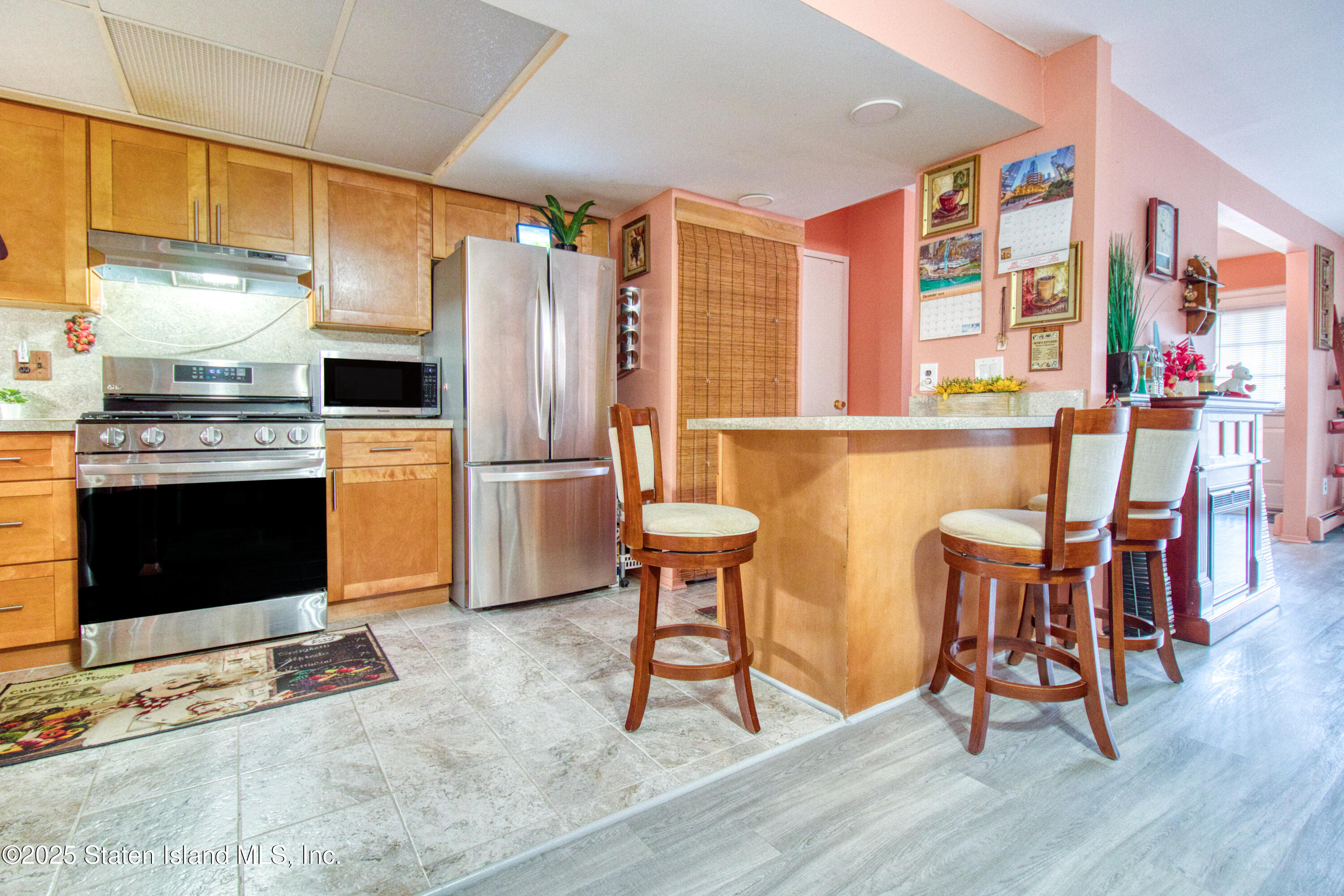 52 Racal Court, Unit A2 Staten Island, NY 10314 - Photo 4 of 28 a kitchen with stainless steel appliances granite countertop a stove top oven a refrigerator and a dining table with wooden floor