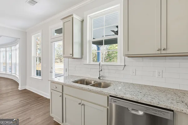 a kitchen with granite countertop a sink and white cabinets with wooden floor