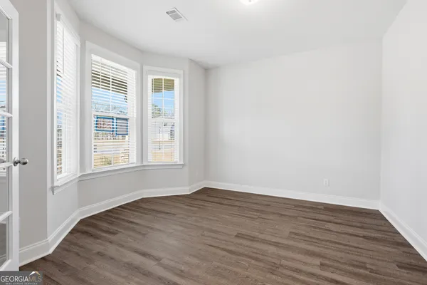 a view of an empty room with wooden floor and a window