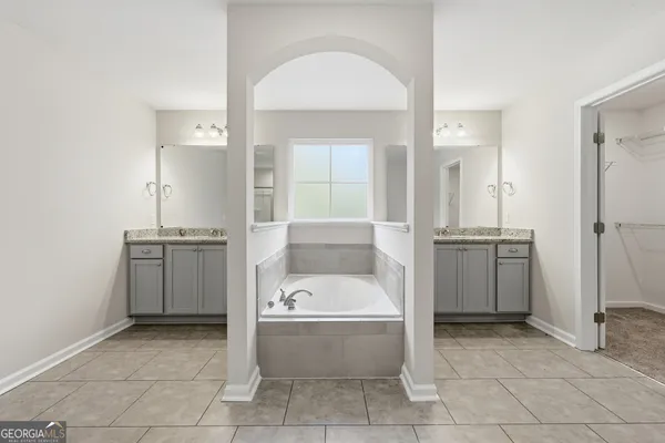 a bathroom with a tub a sink and mirror