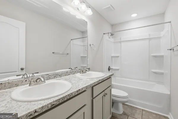 a bathroom with a granite countertop sink a toilet a mirror and shower