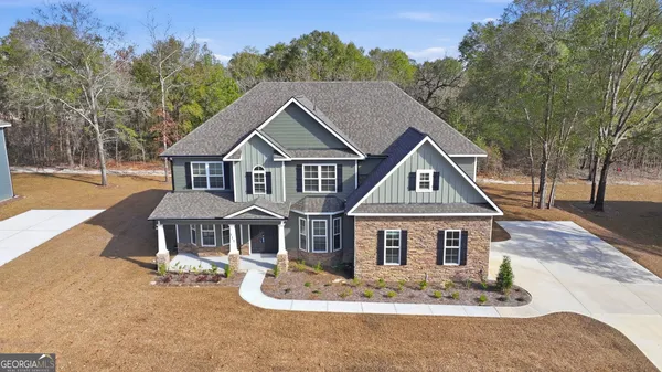 an aerial view of a house with swimming pool and large trees