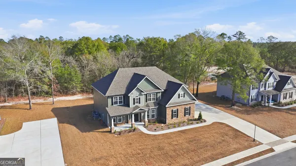 an aerial view of a house with swimming pool and large trees