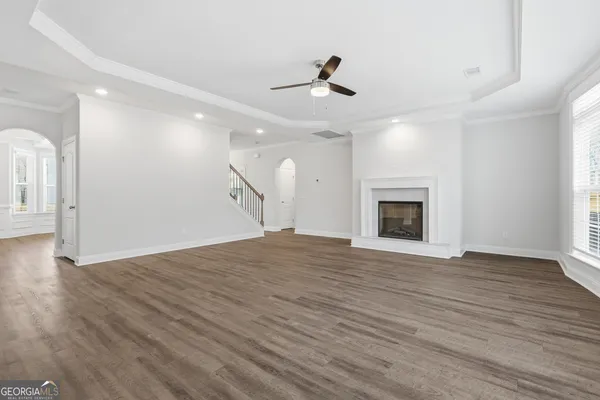 a view of an empty room with wooden floor fireplace and a window