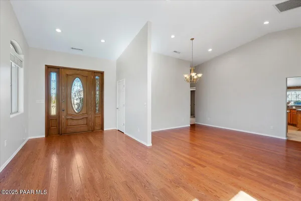 an empty room with wooden floor fireplace and chandelier