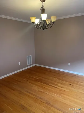 a view of a room with a chandelier fan and wooden floor