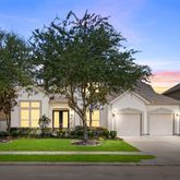 a front view of a house with a garden and trees