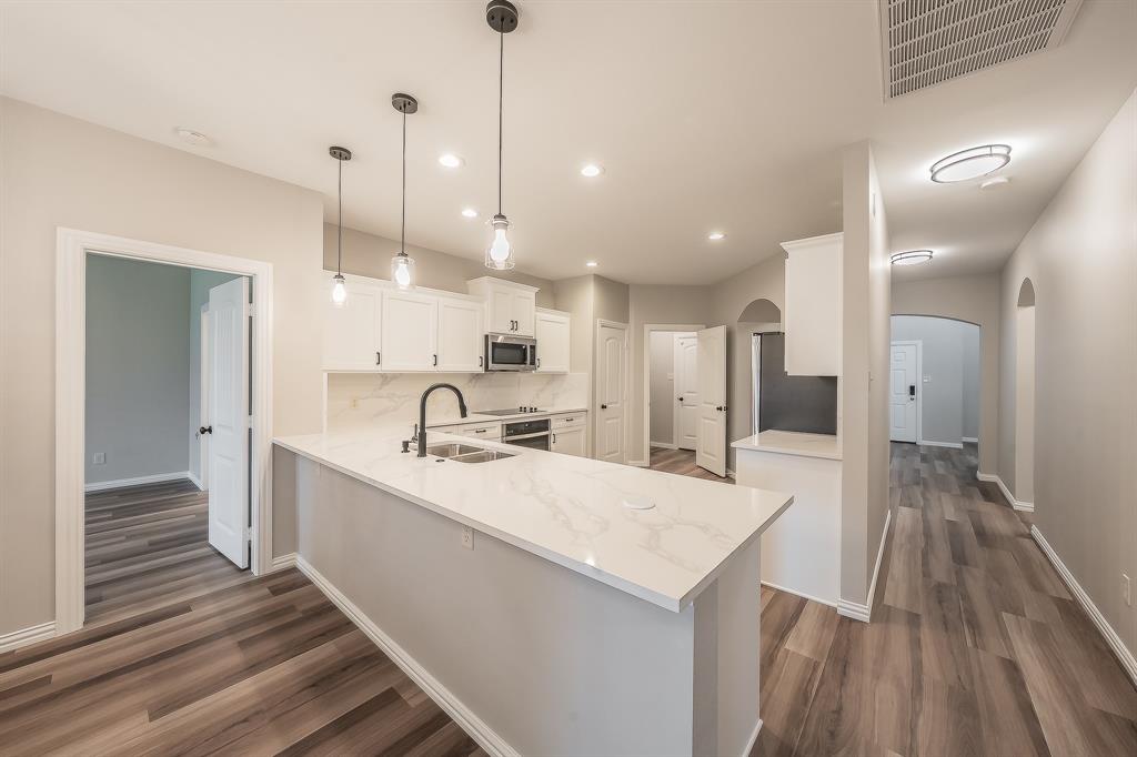 412 Hideaway Road McKinney, TX 75072 - Photo 15 of 40 a large kitchen with kitchen island a sink dishwasher a refrigerator and wooden floor