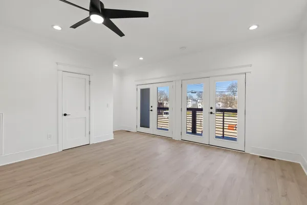 an empty room with wooden floor and ceiling fan