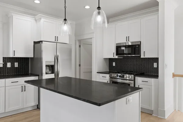 a kitchen with stainless steel appliances granite countertop a refrigerator a sink a stove and a wooden floors