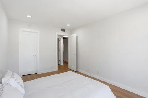 a view of a room with a bed and wooden floor