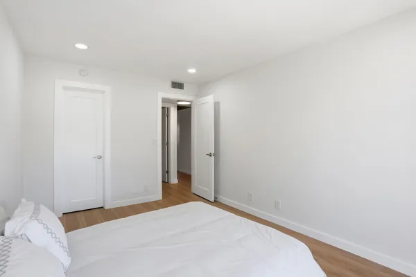 a view of a room with a bed and wooden floor