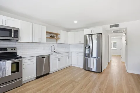 a kitchen with stainless steel appliances granite countertop a refrigerator stove and white cabinets