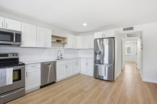 a kitchen with stainless steel appliances granite countertop a refrigerator stove and white cabinets