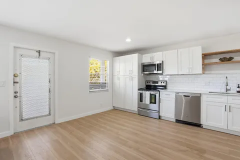 a kitchen with granite countertop white cabinets and stainless steel appliances