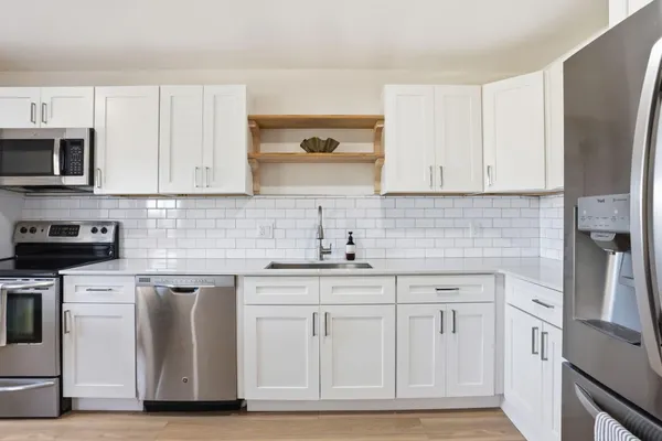 a kitchen with white cabinets appliances and sink