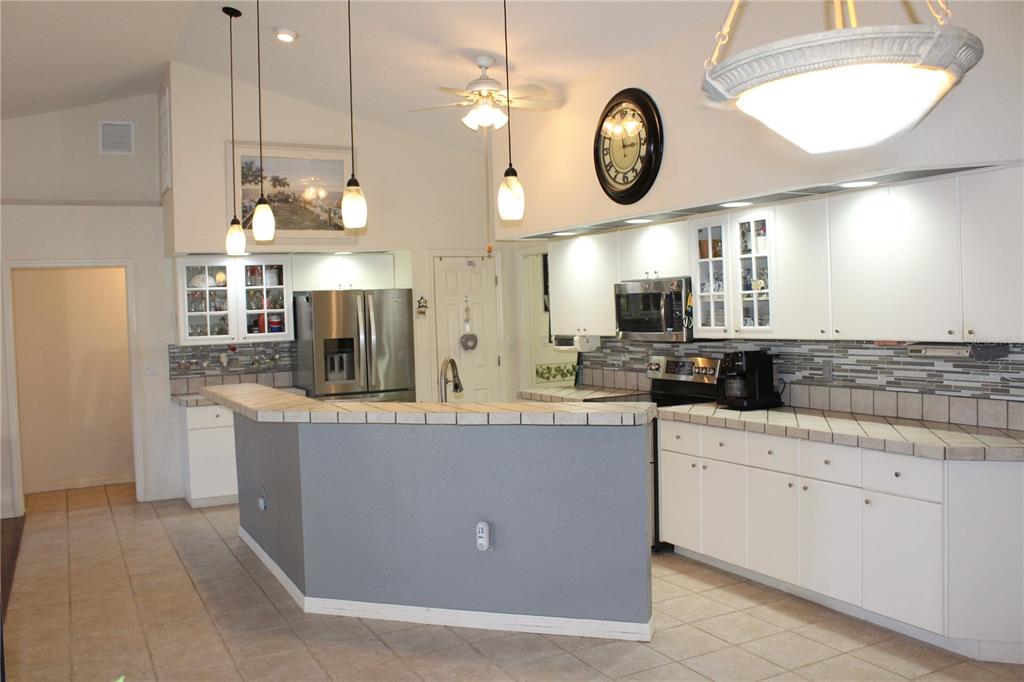 74 Belem Street Punta Gorda, FL 33983 - Photo 2 of 34 a large kitchen with kitchen island granite countertop a sink a stove and a clock on the wall