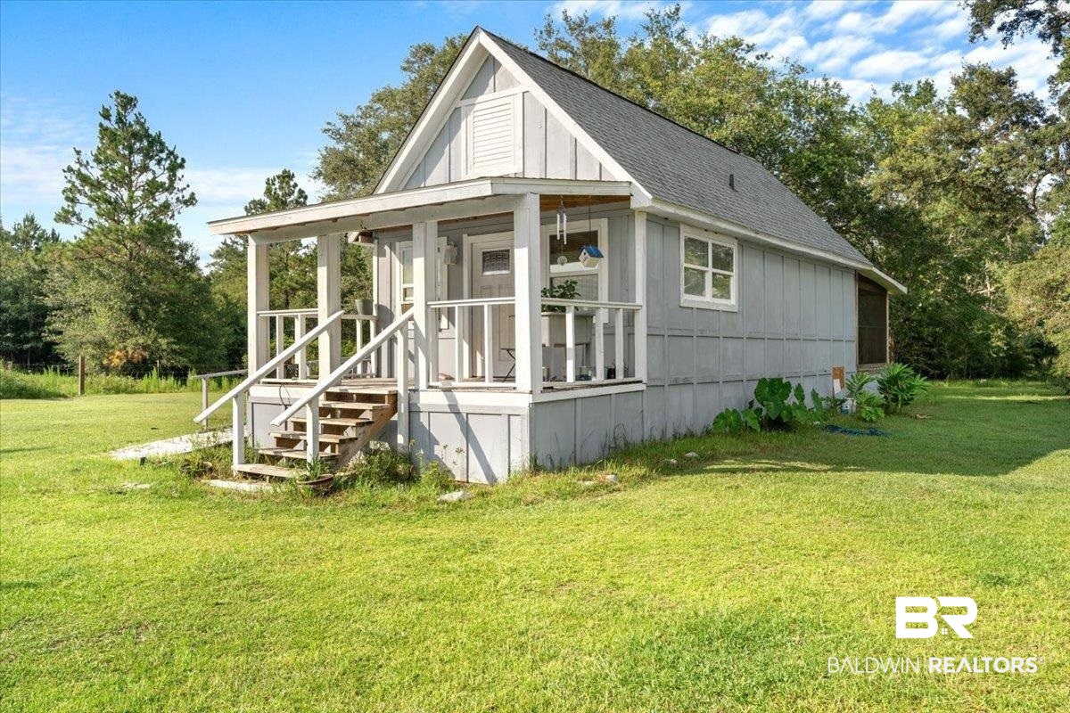 21011 River Road Robertsdale, AL 36567 - Photo 22 of 29 Charming cottage exterior featuring a covered front porch with white railings, a light gray siding, and a dark shingle roof