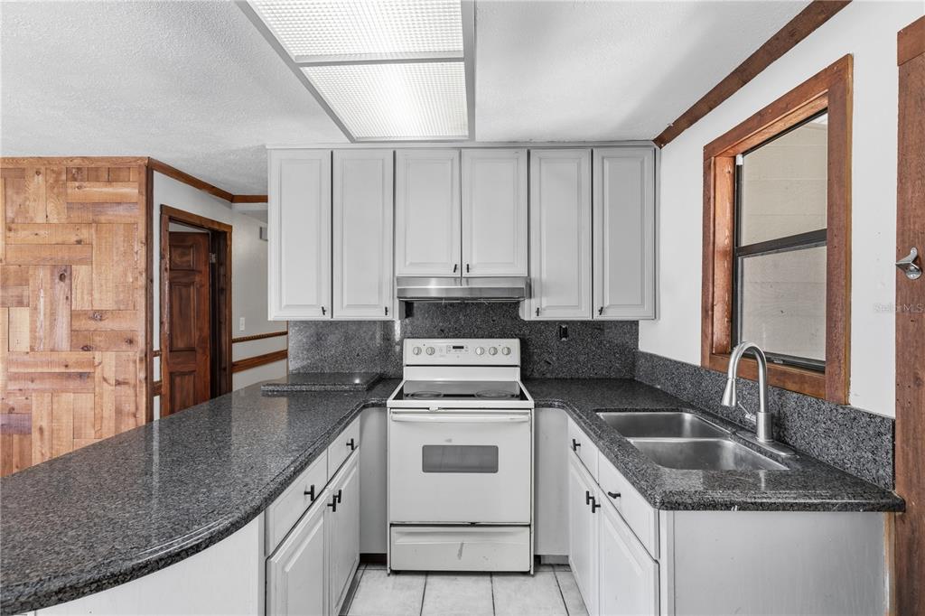 10301 Trail Ridge Lane Tampa, FL 33624 - Photo 9 of 35 a kitchen with granite countertop a sink stove and cabinets