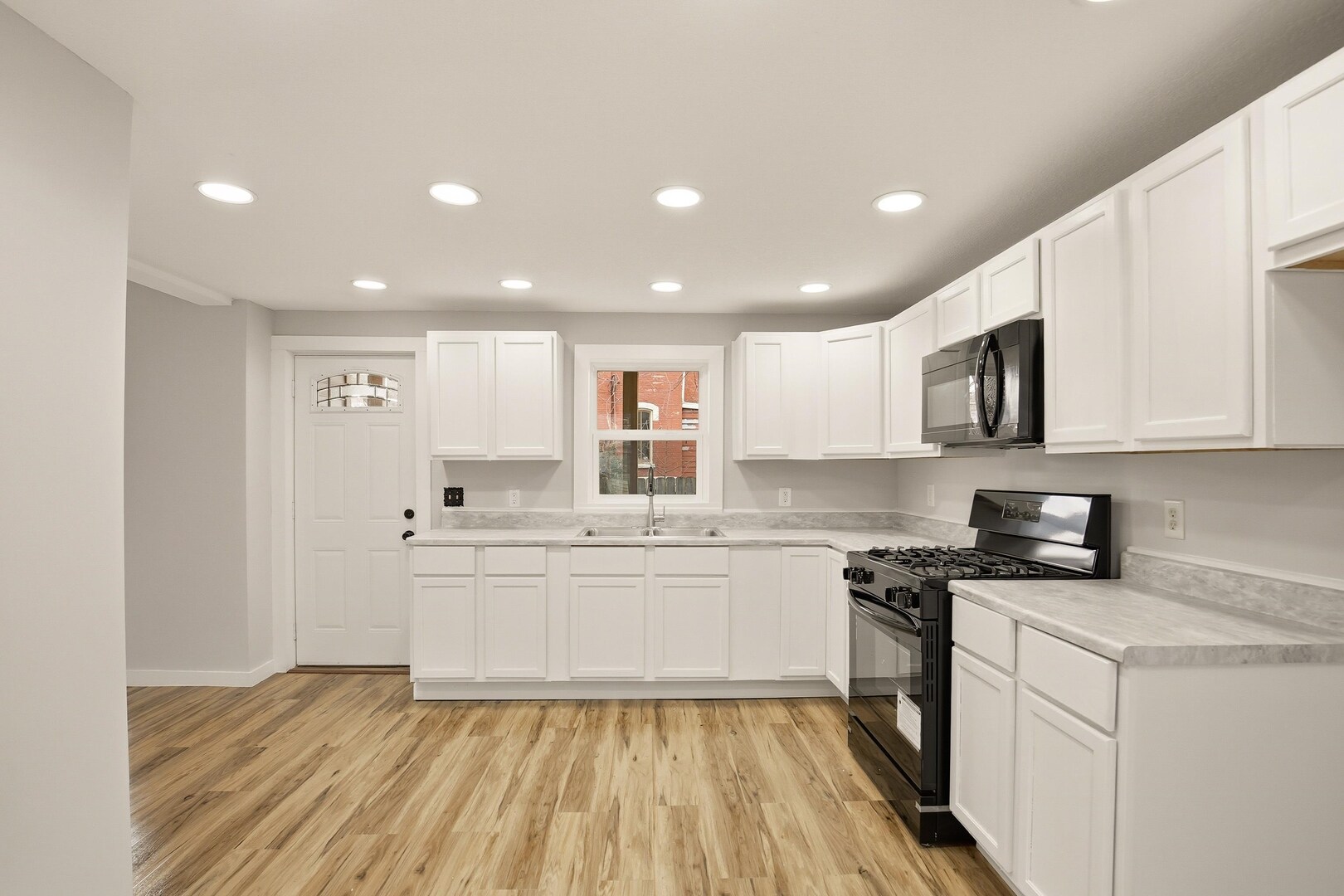 1928 8th Avenue Rock Island, IL 61201 - Photo 14 of 33 a kitchen with stainless steel appliances granite countertop a stove top oven a sink dishwasher and white cabinets with wooden floor
