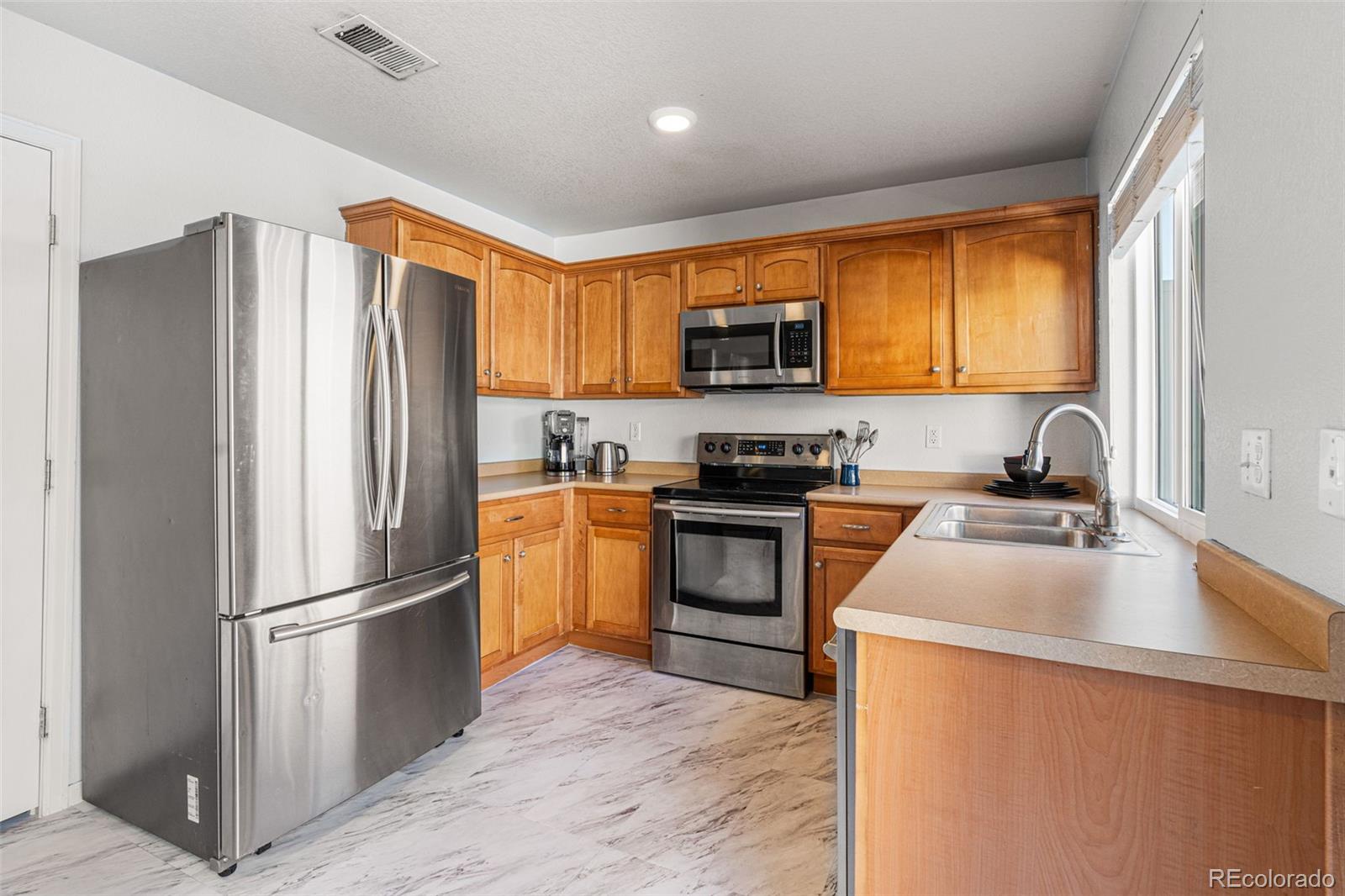 19525 Robins Drive Denver, CO 80249 - Photo 15 of 44 a kitchen with a refrigerator a stove top oven a sink and dishwasher