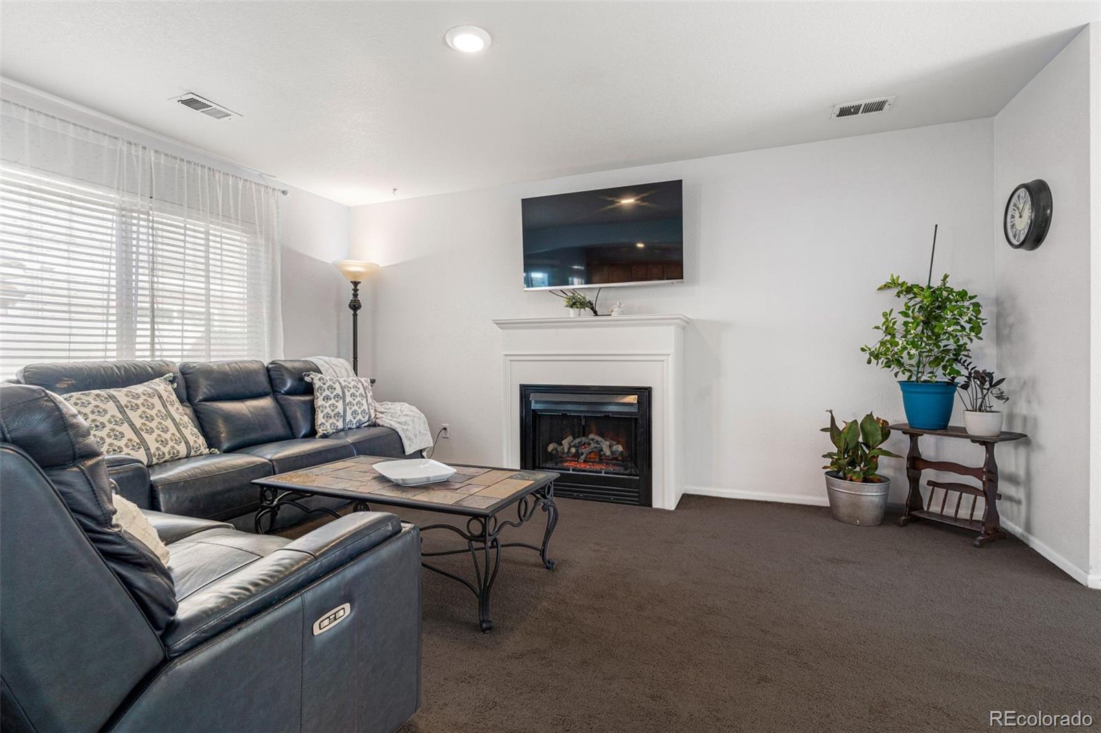 19525 Robins Drive Denver, CO 80249 - Photo 7 of 44 a living room with furniture a flat screen tv and a fireplace