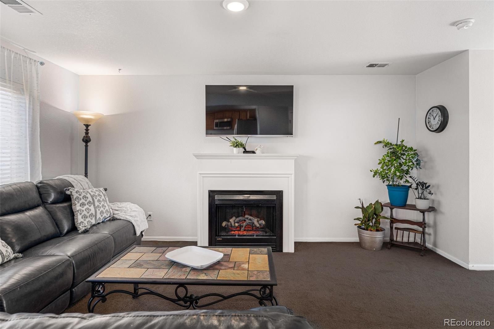 19525 Robins Drive Denver, CO 80249 - Photo 8 of 44 a living room with furniture a fireplace and a flat screen tv
