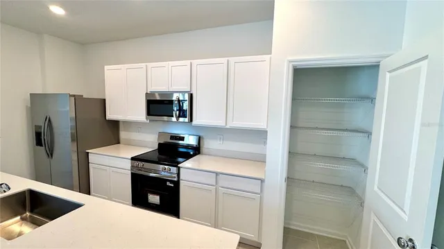 a kitchen with a refrigerator sink and white cabinets