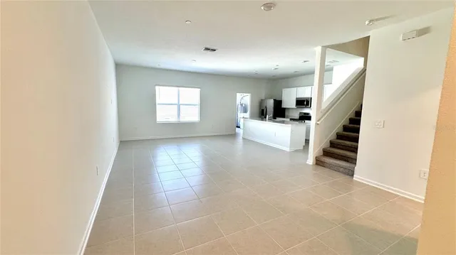 a view of an empty room with stairs and a window