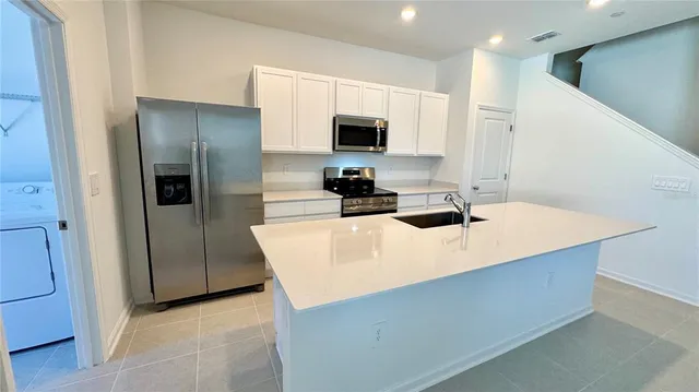 a kitchen with stainless steel appliances a microwave a sink a refrigerator and white cabinets