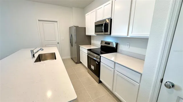a kitchen with a sink a microwave a refrigerator and cabinets