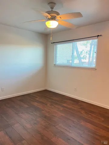 a view of an empty room with window and wooden floor