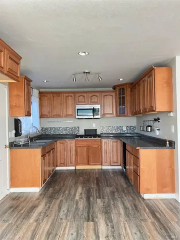 a kitchen with stainless steel appliances granite countertop wooden cabinets a window and a sink