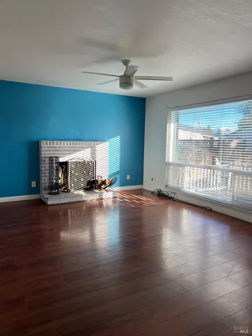 a view of empty room with fireplace and wooden floor