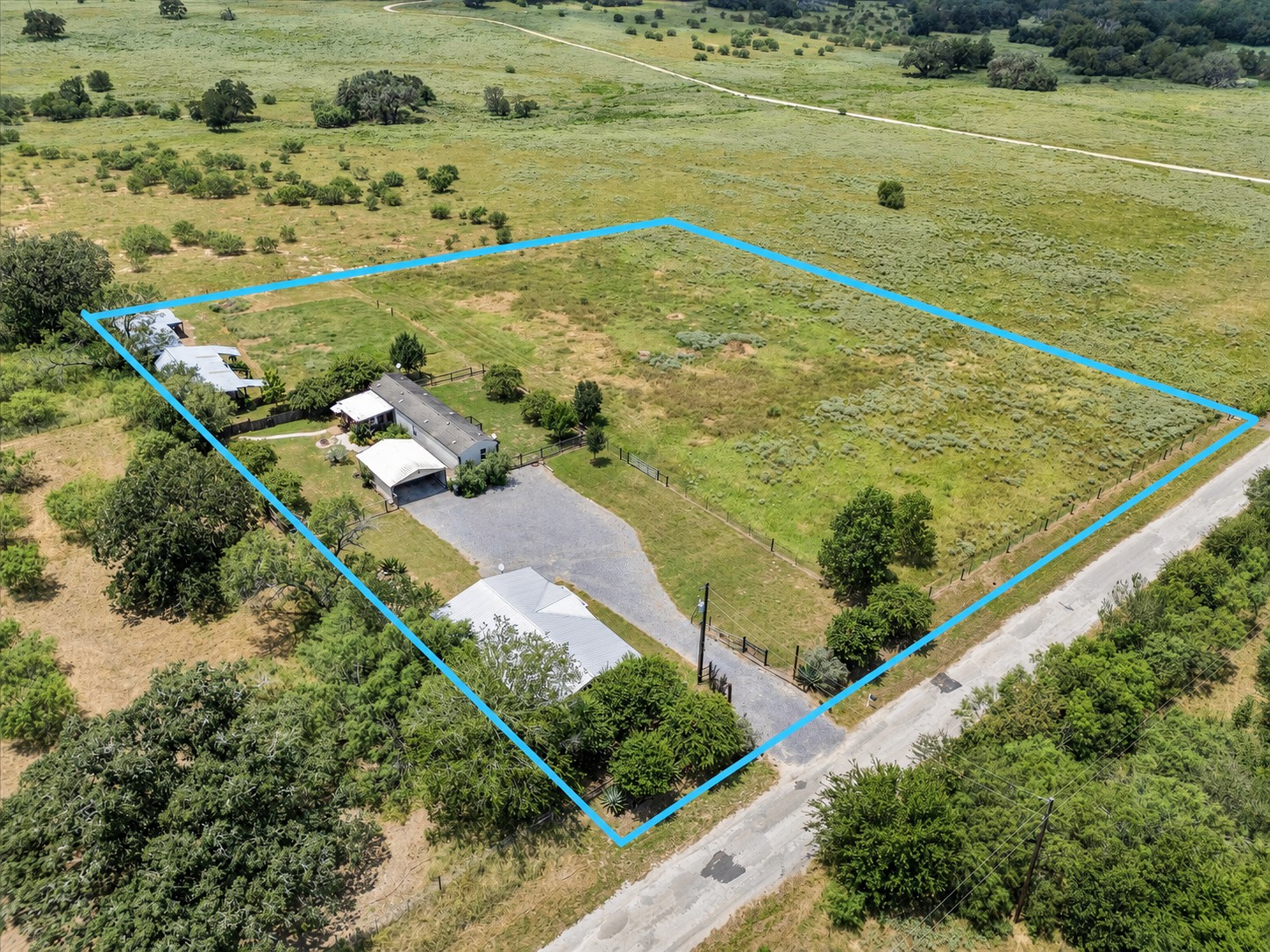 1500 Wattsville Road Luling, TX 78648 - Photo 5 of 38 An expansive rural property, defined by a vibrant blue outline, presents a tranquil setting with ample space and a private driveway.
