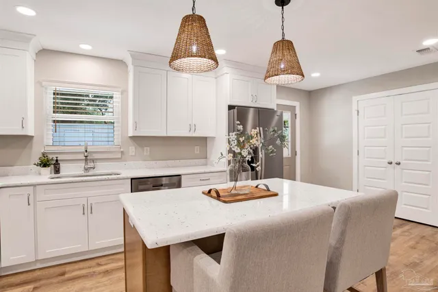 a kitchen with stainless steel appliances kitchen island granite countertop a sink a refrigerator and wooden cabinets