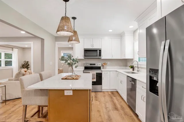 a kitchen with a refrigerator a stove top oven a sink dishwasher and a dining table with wooden floor