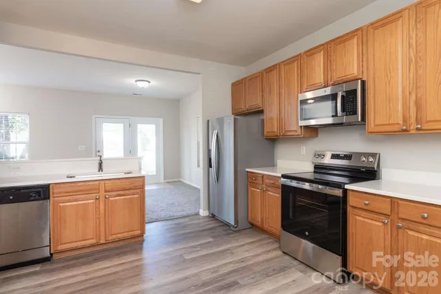 a kitchen with stainless steel appliances granite countertop wooden cabinets a stove a sink and dishwasher with wooden floor